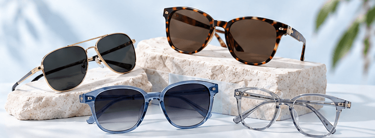 Tortoise, aviator, blue and clear eyewear arranged on pale stone